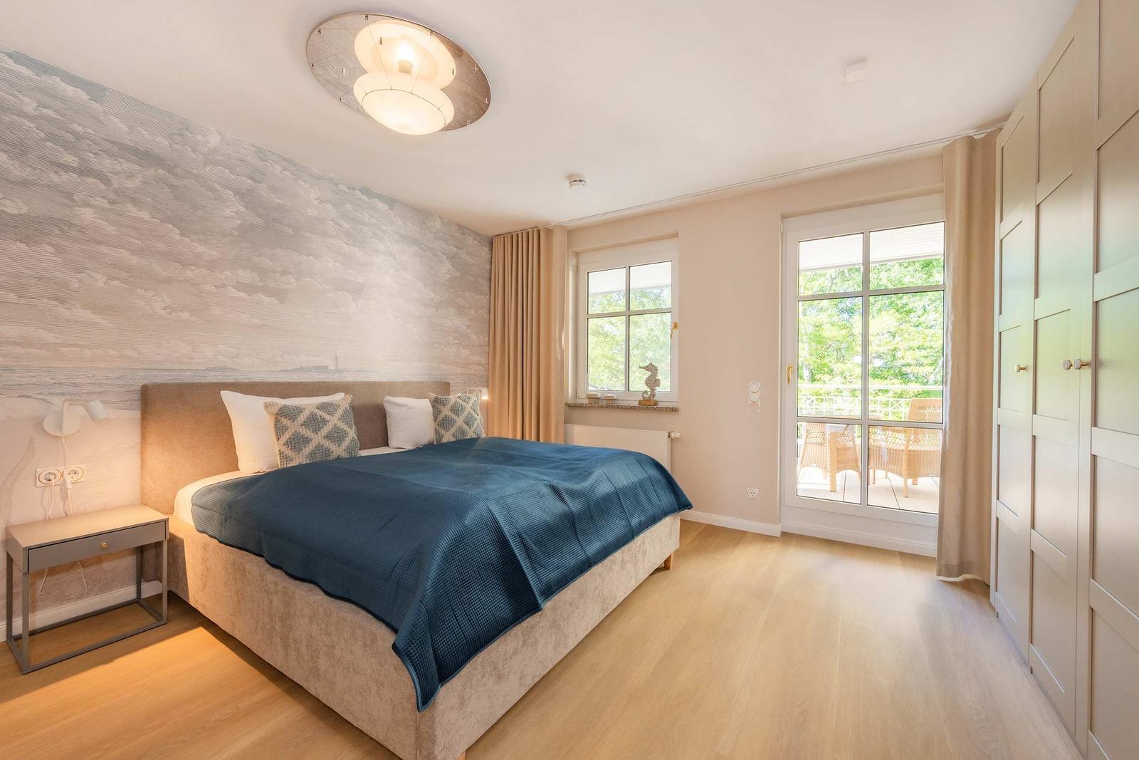 Schlafzimmer mit Bett, Nachttisch und Balkonansicht.
