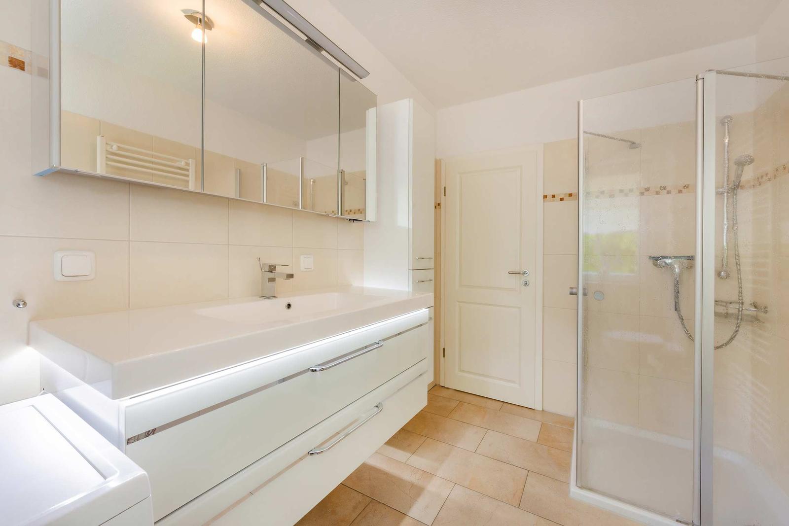 Badezimmer mit Dusche, Waschbecken und Spiegelschrank.