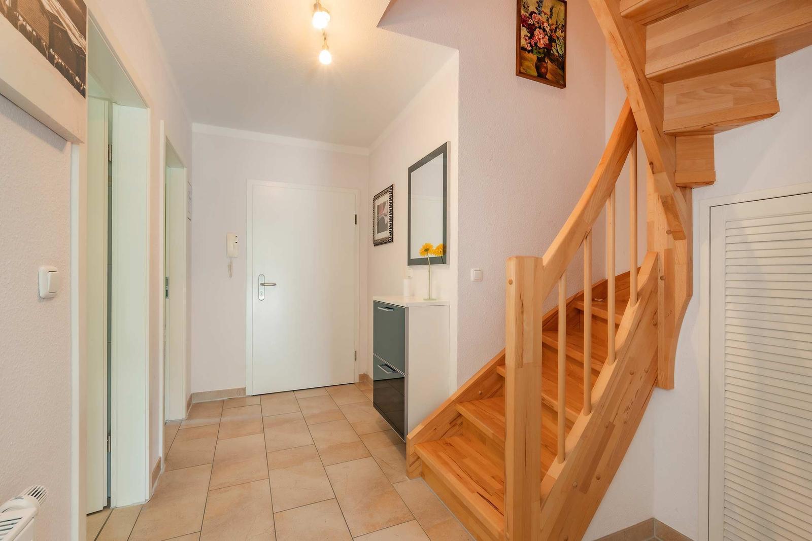 Hausgang mit Holztreppe, Spiegel und Tür