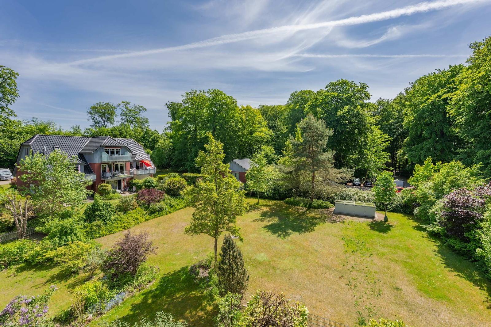 Haus mit Garten und Bäumen unter blauem Himmel.