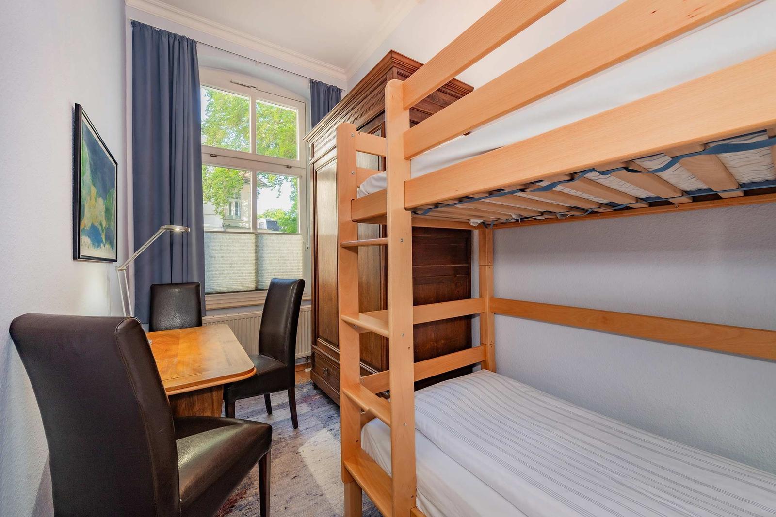 Zimmer mit Doppelstockbett, Schreibtisch und Fenster mit Blick.
