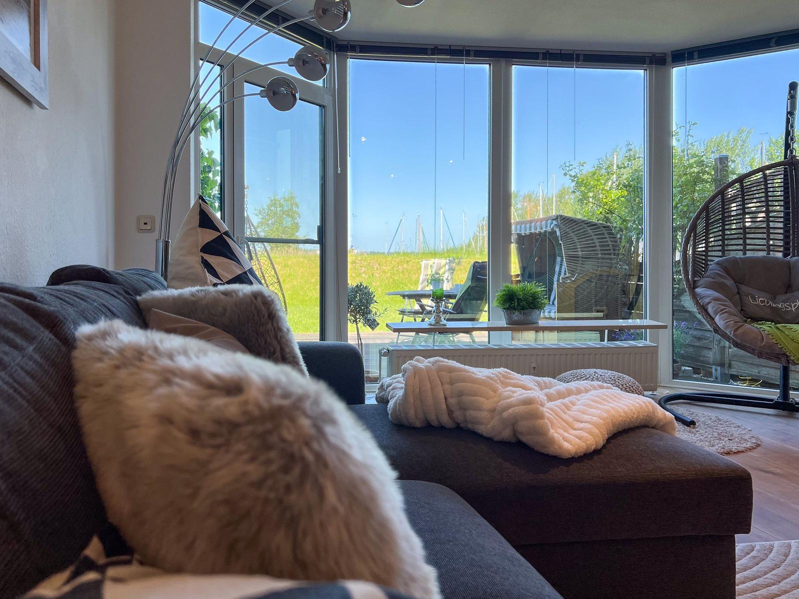 Wohnzimmer mit Sofa, Decke und Blick auf Garten und Himmel