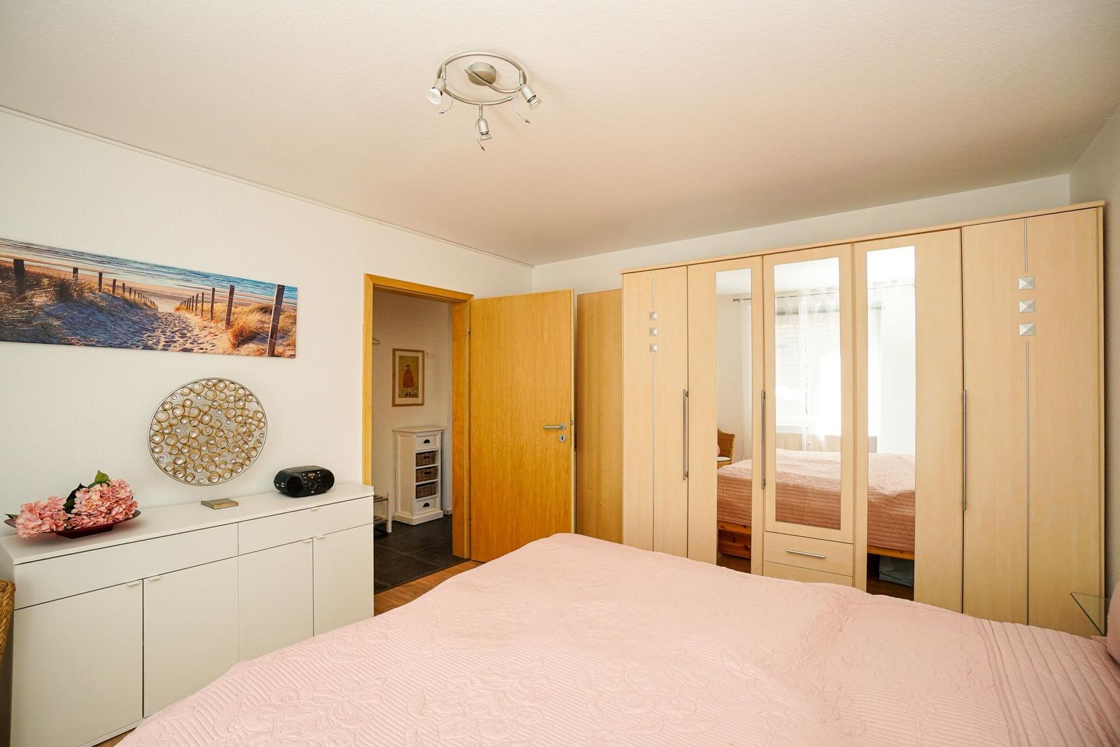 Schlafzimmer mit Bett, Kleiderschrank und Wandbild