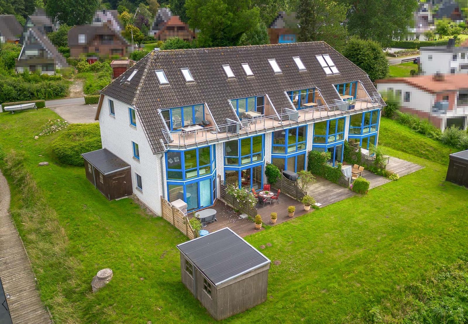 Modernes Haus mit großem Garten und Terrasse mit blauen Fenstern.