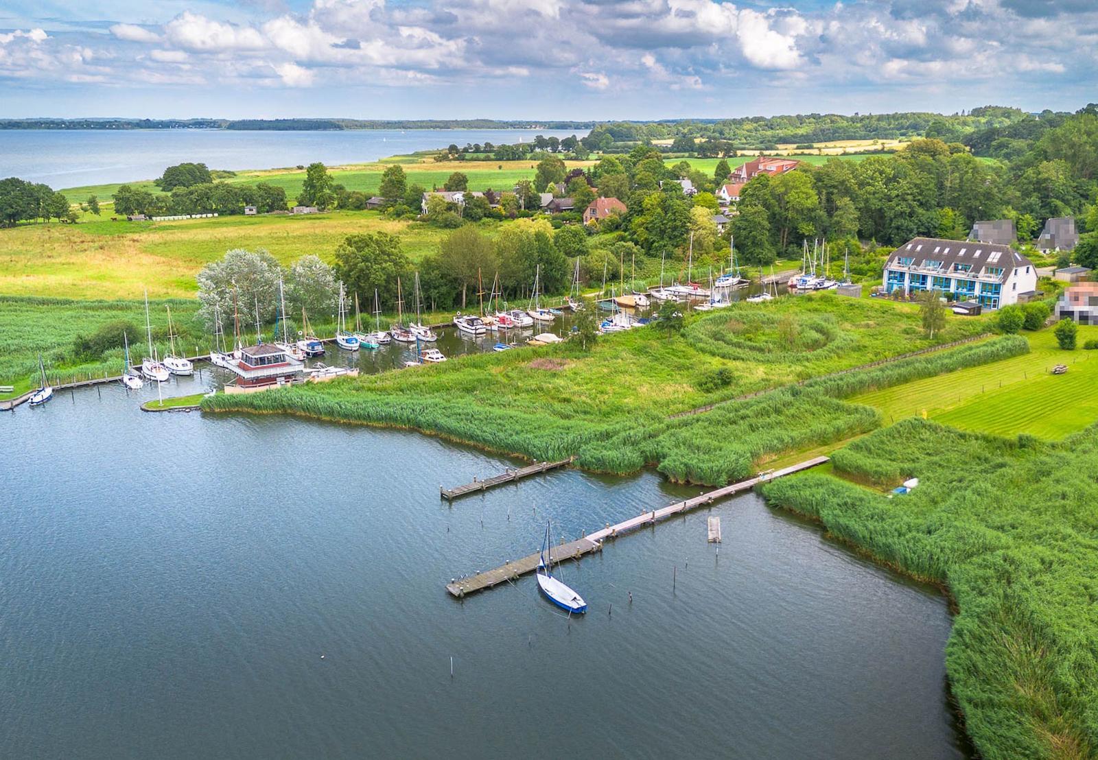 Seeufer mit Bootshäfen, grünen Wiesen und Häusern
