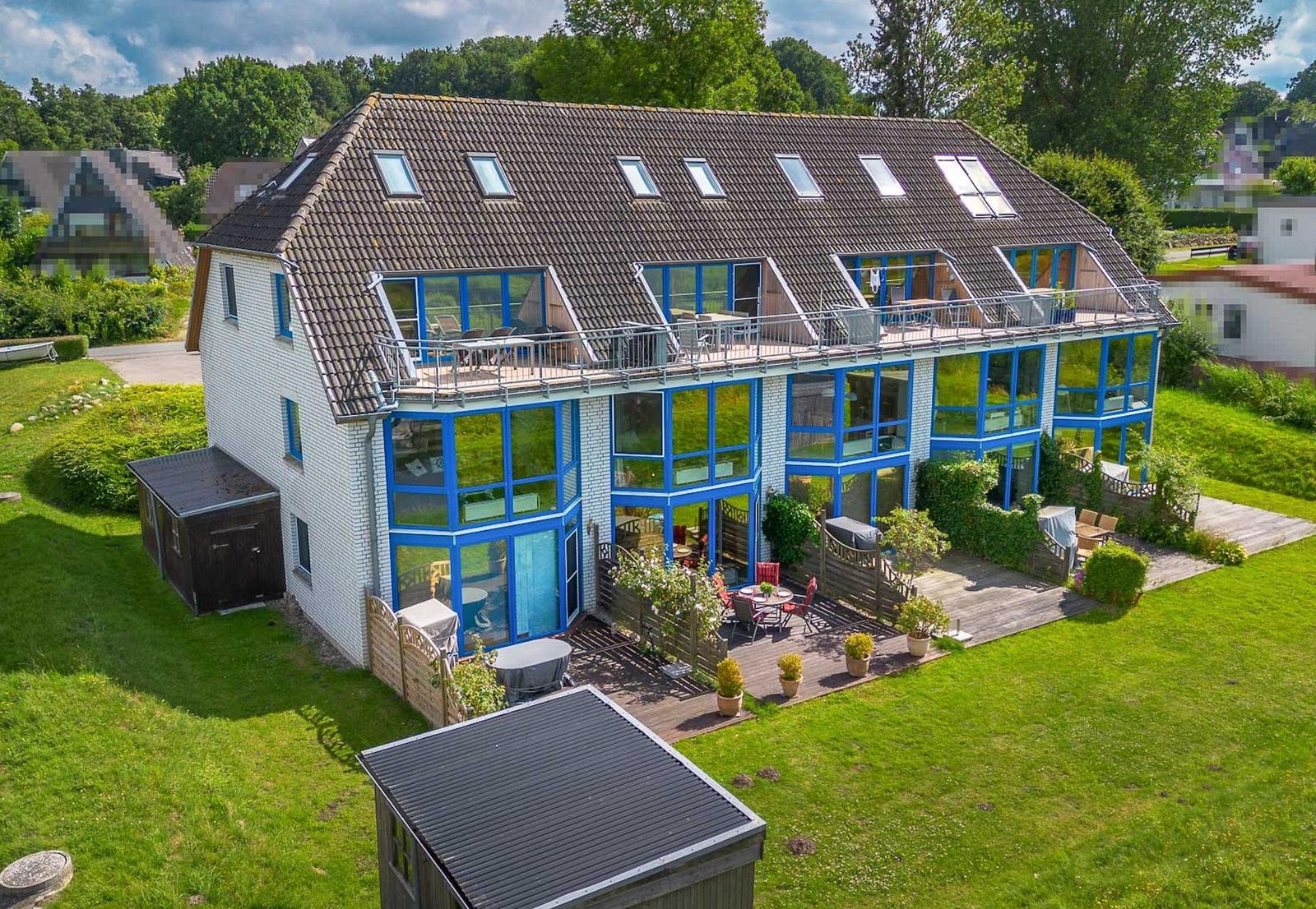 Moderne Villa mit blauen Fenstern und Dachterrasse. Großer Garten mit Terrasse und Grillplatz.