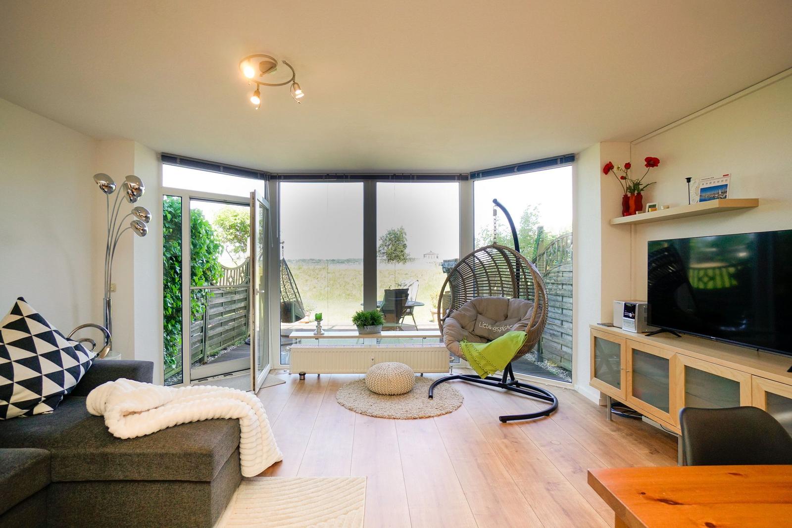 Wohnzimmer mit Sitzgelegenheiten, Fernseher und Blick auf die Terrasse.