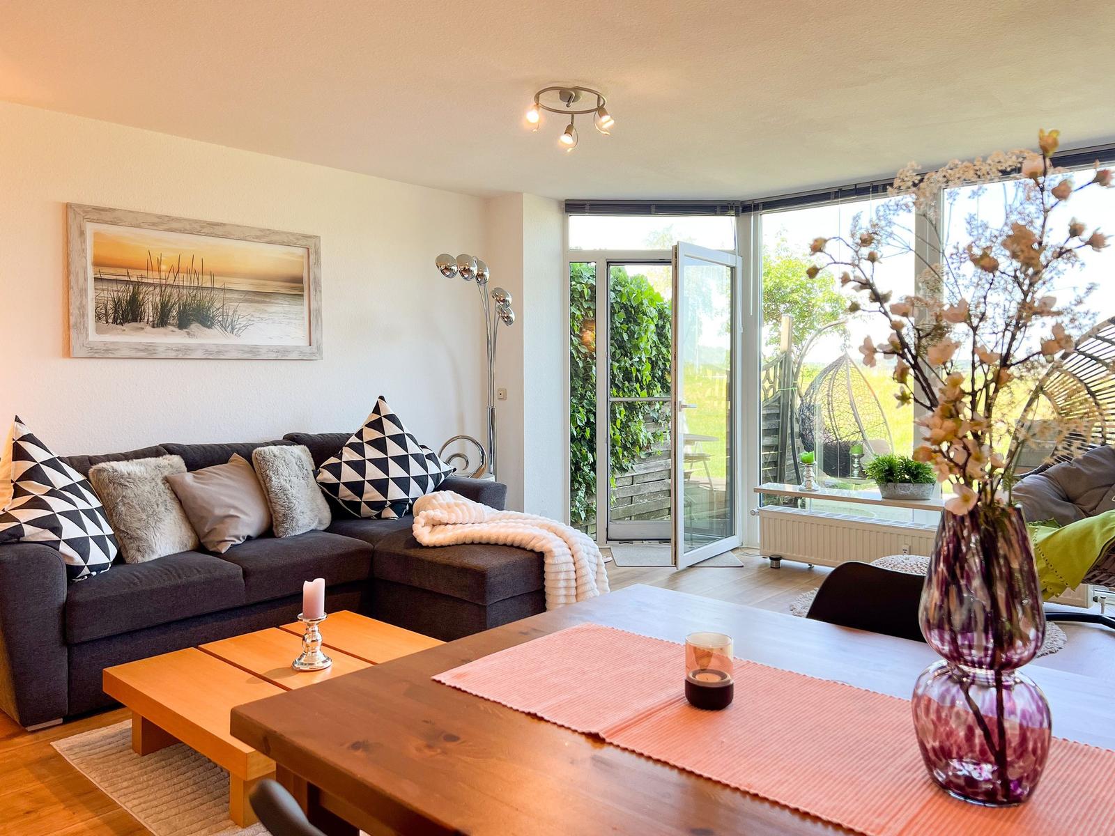 Wohnbereich mit Sofa, Esstisch und Blick auf Garten