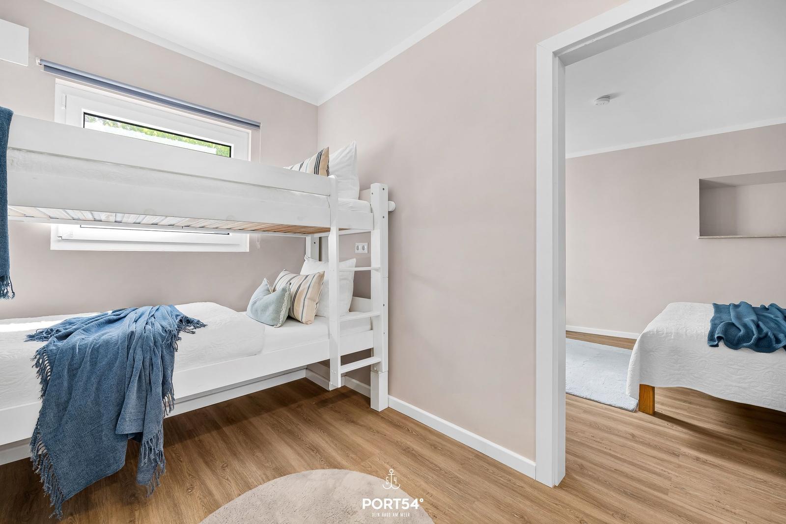 Zimmer mit Doppelstockbett und Blick auf Fenster. Nebenraum mit Einzelbett.