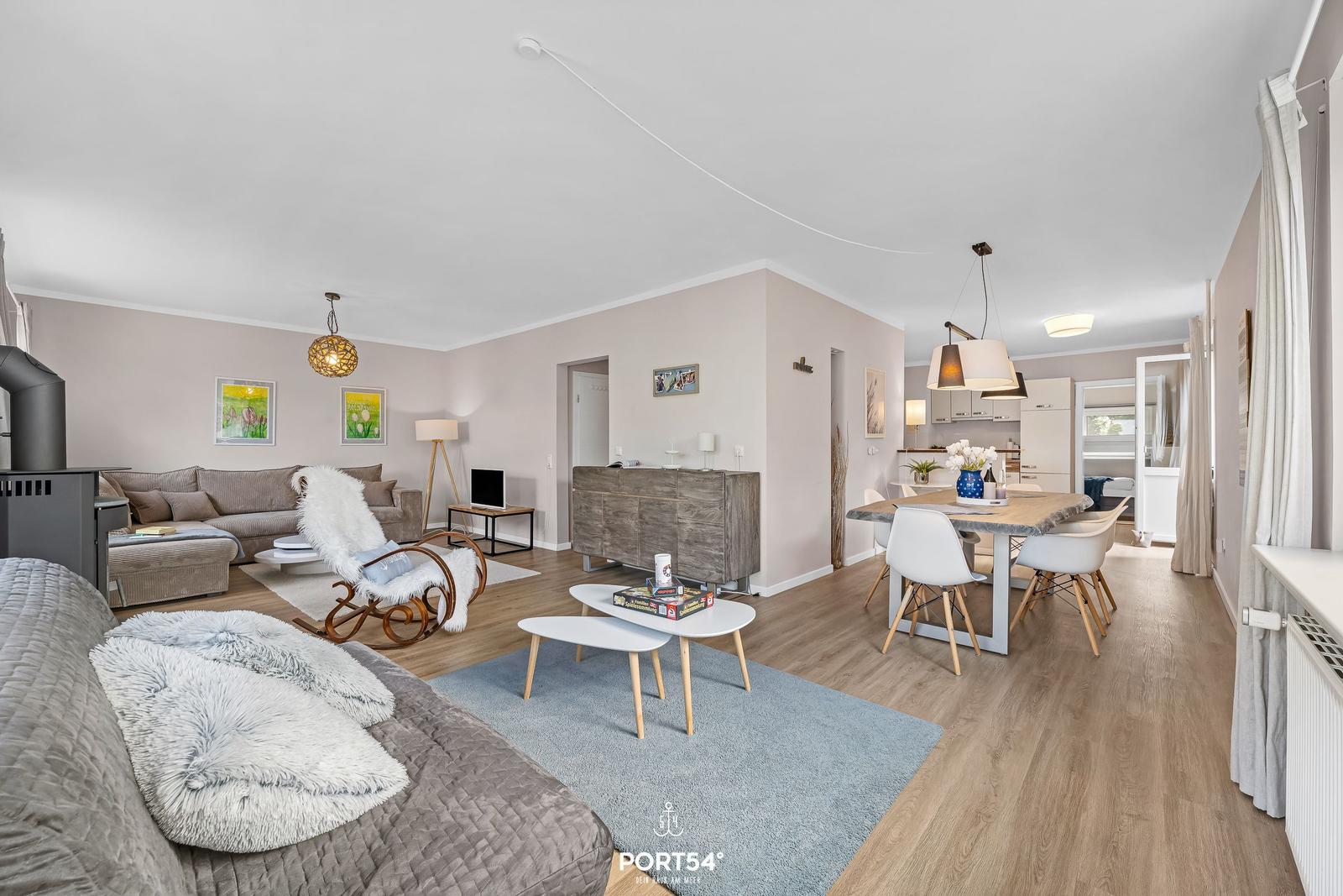 Wohn- und Essbereich mit Holzboden, Sofa, Esstisch und Küchenbereich.