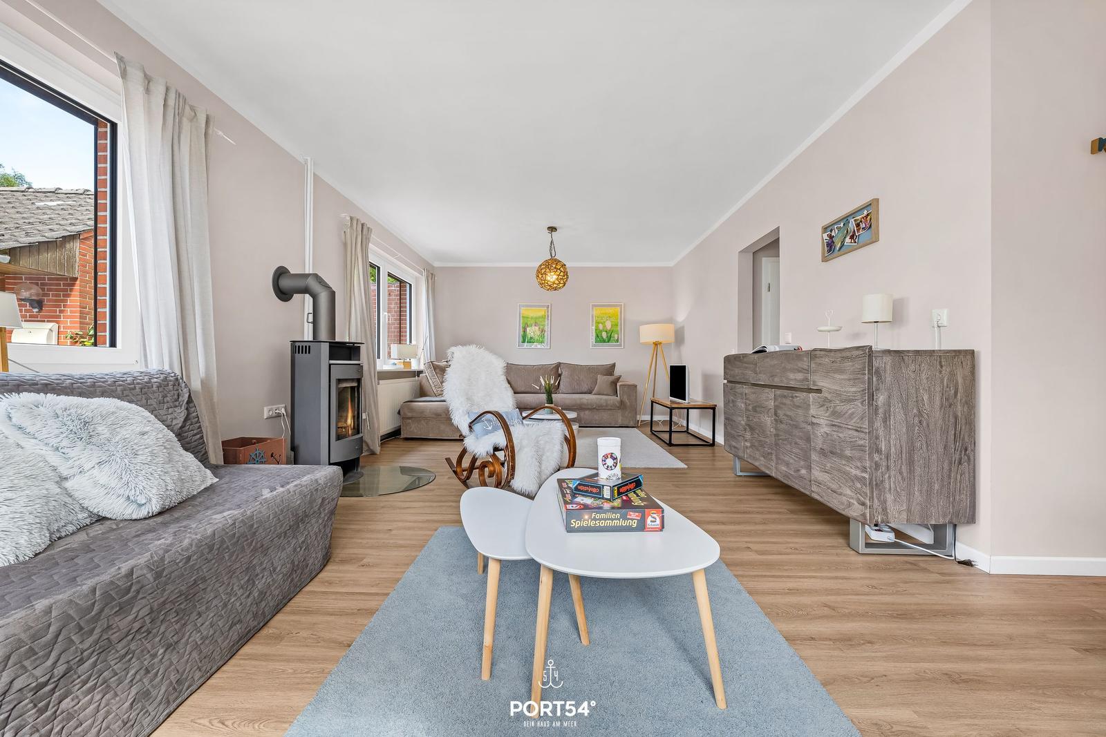 Wohnzimmer mit Sofa, Kamin und Holzboden. Tisch mit Spielen und Wandbildern.