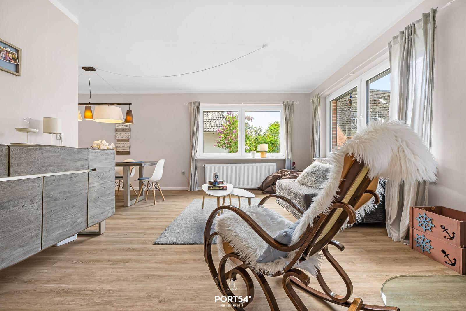 Wohnzimmer mit Holzboden, Sessel, Couch und Fenster. Dekoration mit Schiffsmotiven.