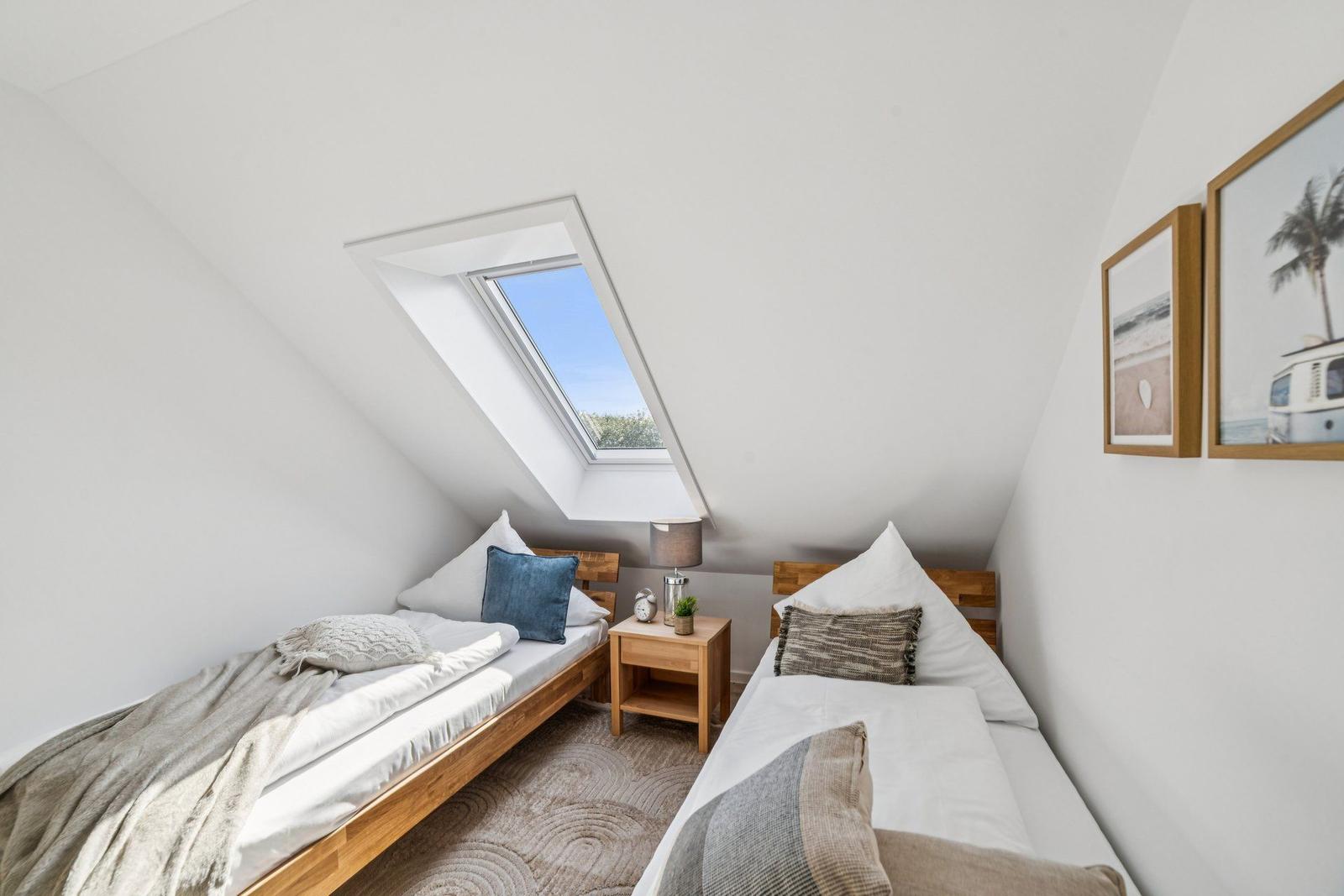 Zwei Betten unter Dachschrägen mit Dachfenster und Bildern an der Wand.