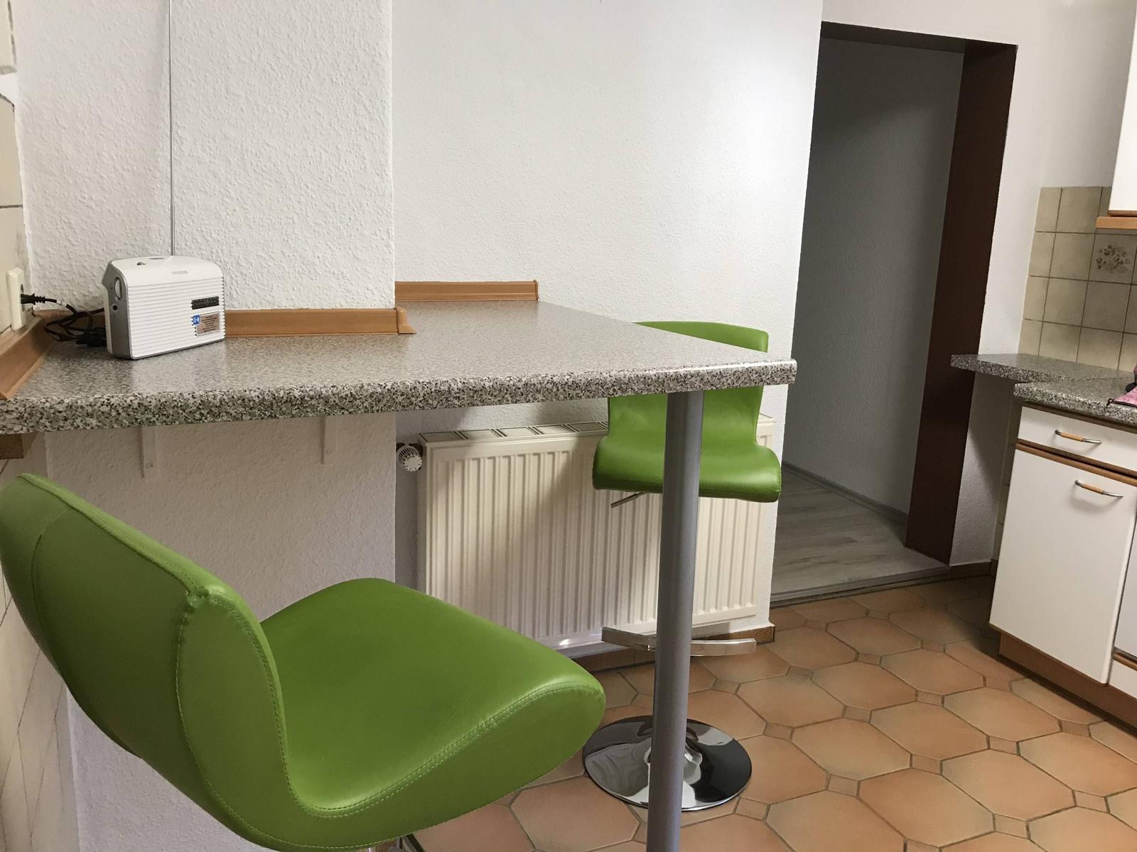 Küchenbereich mit grünen Barhockern und Arbeitsplatte.