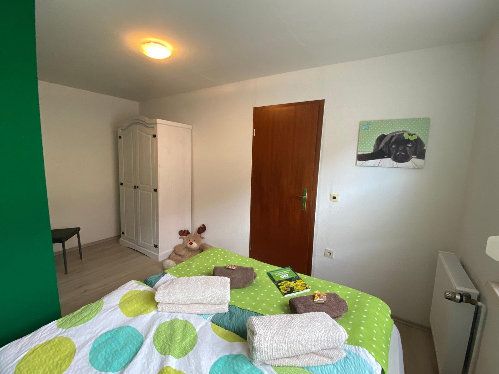 Schlafzimmer mit Bett, Kleiderschrank und Wandbild eines Hundes.