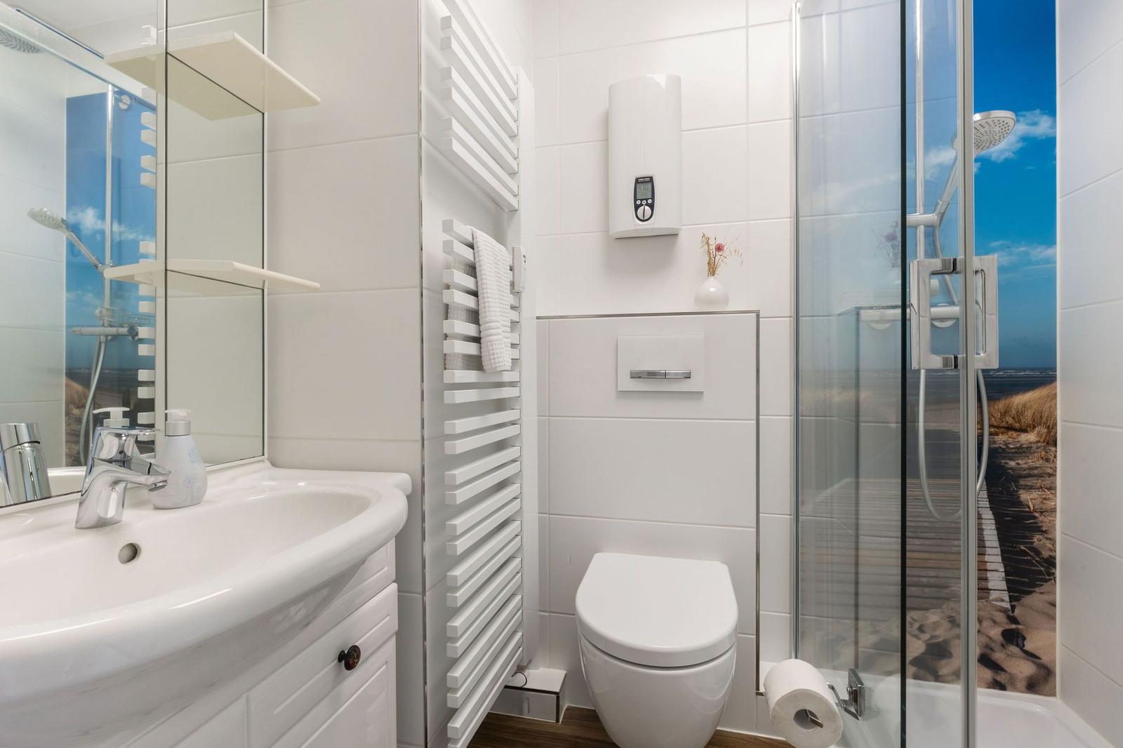 Badezimmer mit Duschraum, Toilette und Waschbecken mit Spiegel.