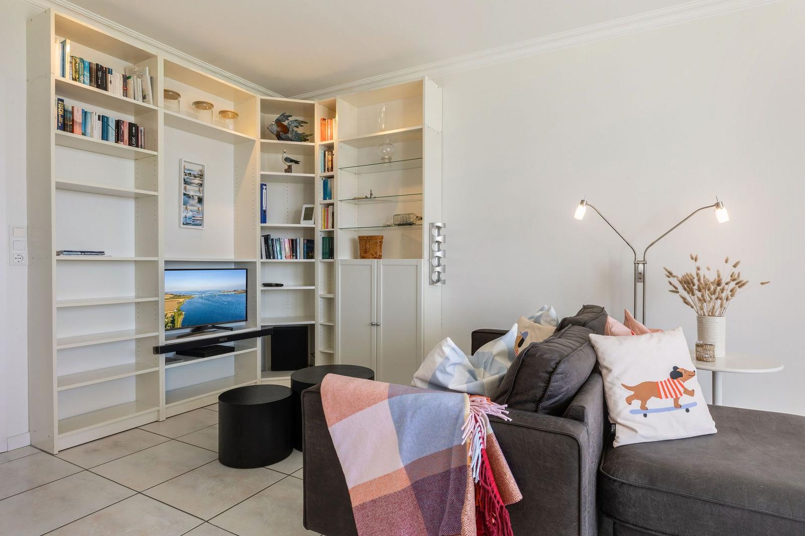 Wohnzimmer mit Sofa, Bücherregal und Fernseher.
