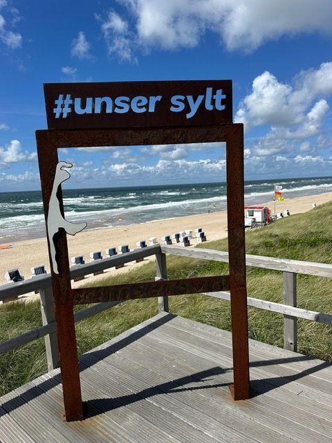 Holzgestell mit Schild #unser sylt auf Strandpromenade