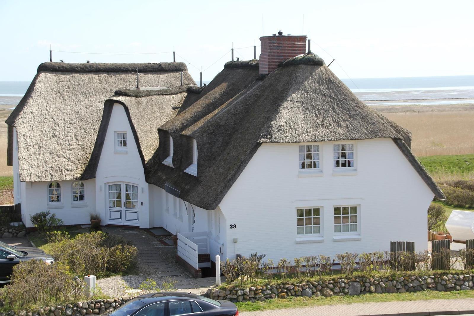 Weißes Haus mit strohgedecktem Dach und Fenstern, Blick auf die Ostsee.