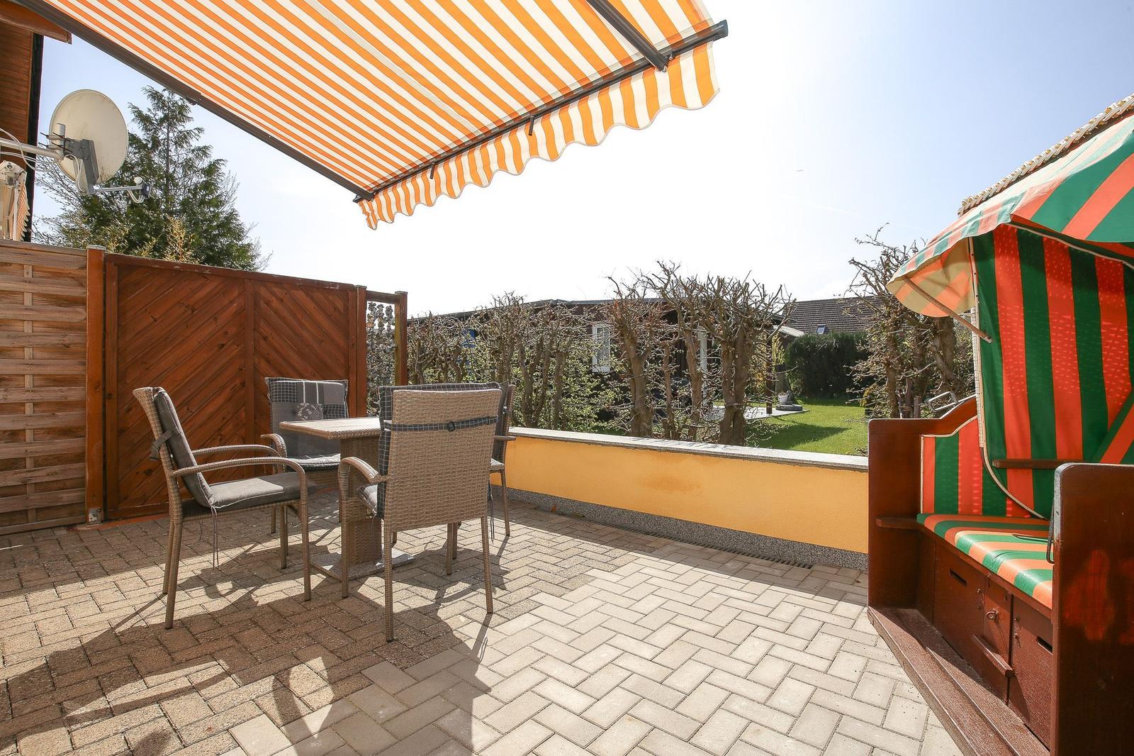 Terrasse mit Sonnenschutz, Tisch, Stühlen und Blick auf Garten