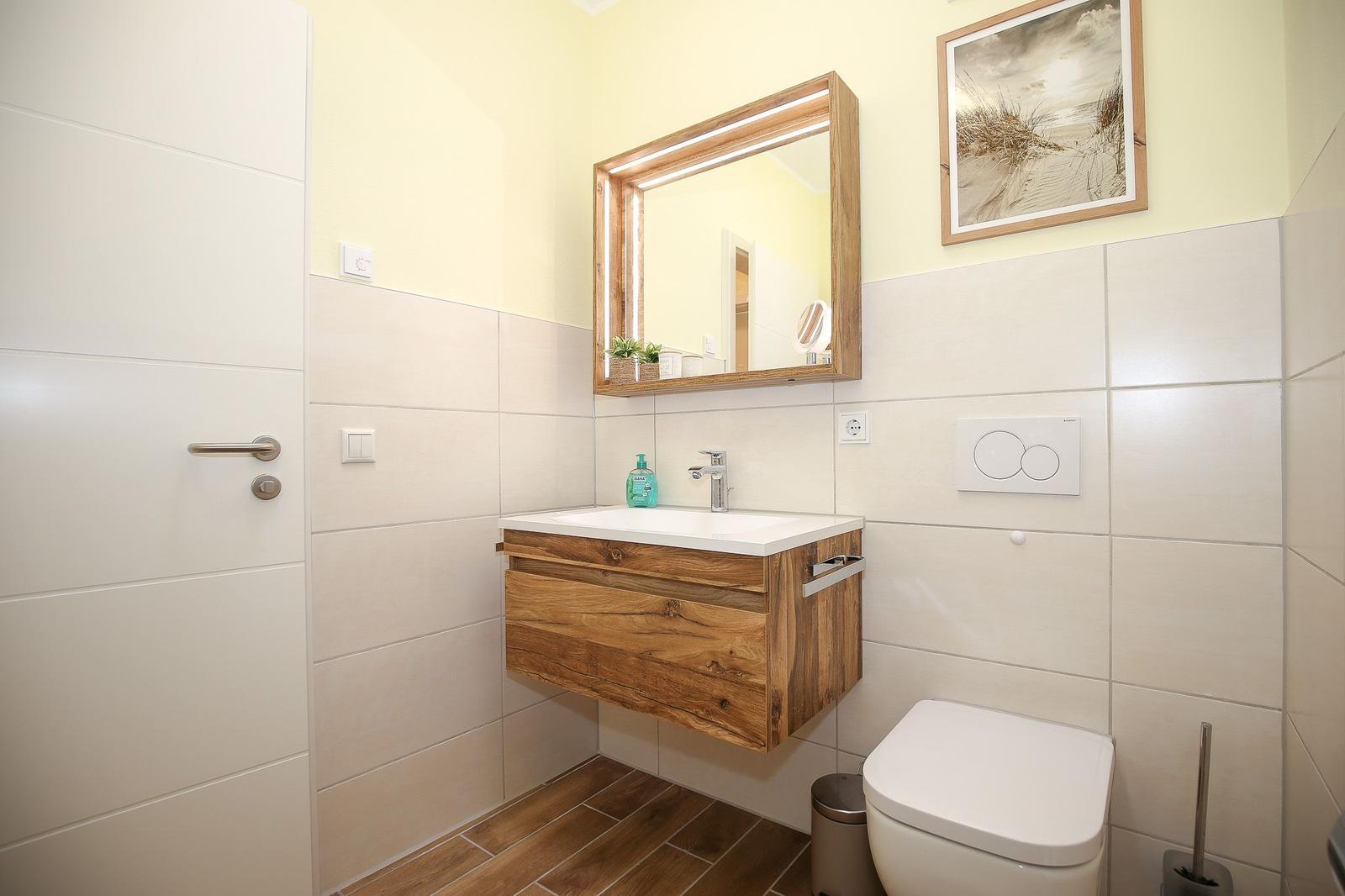 Badezimmer mit Holzwaschbecken, Spiegelschrank und Toilette.