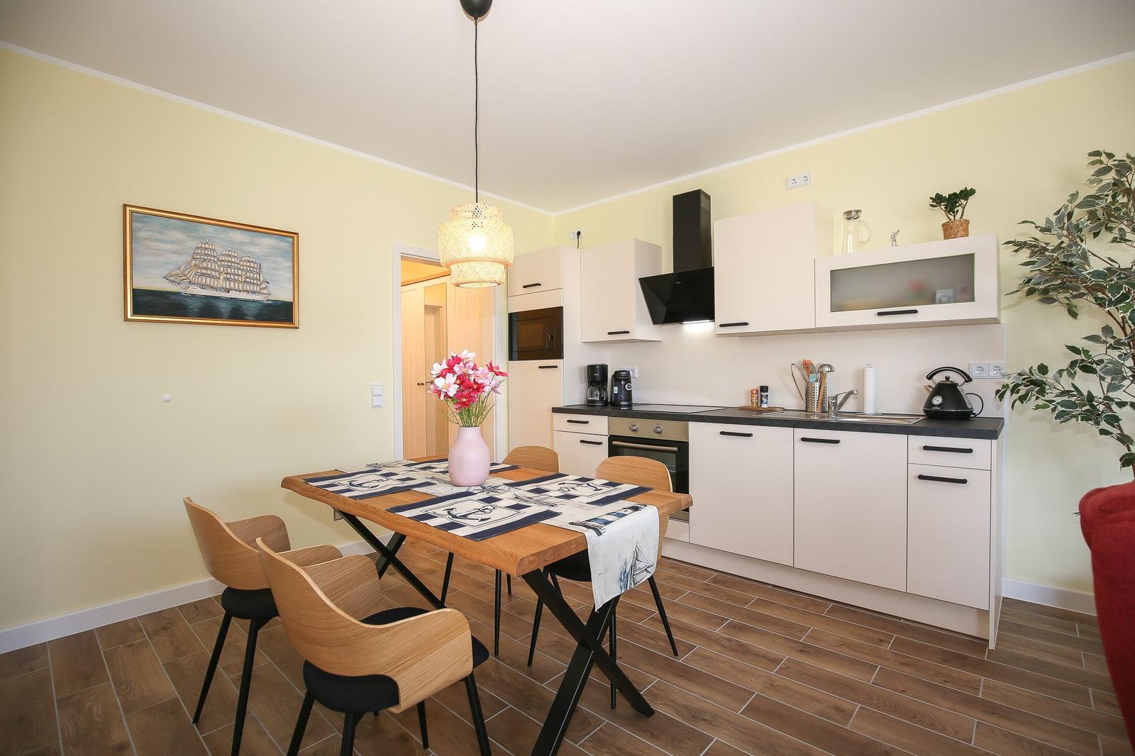 Küche und Essbereich mit Holztisch, Stühlen, Küchenzeile und Wandbild.