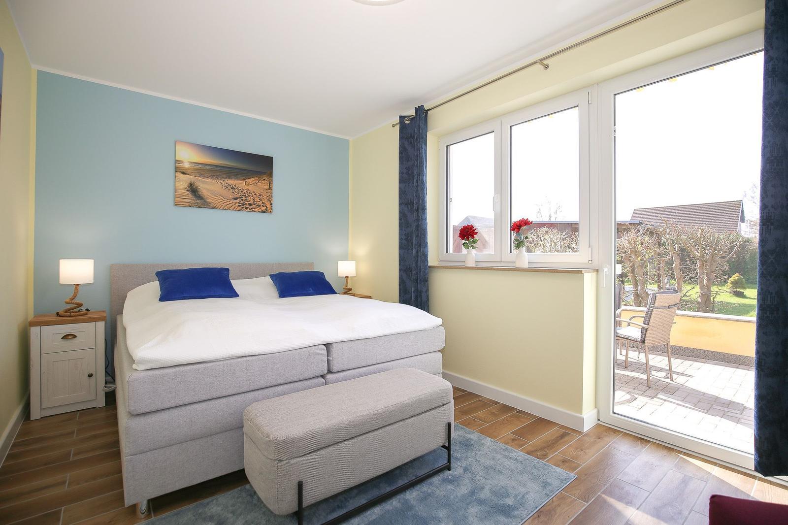Schlafzimmer mit Doppelbett, Fenster und Balkon. Wandbild und Nachttische.
