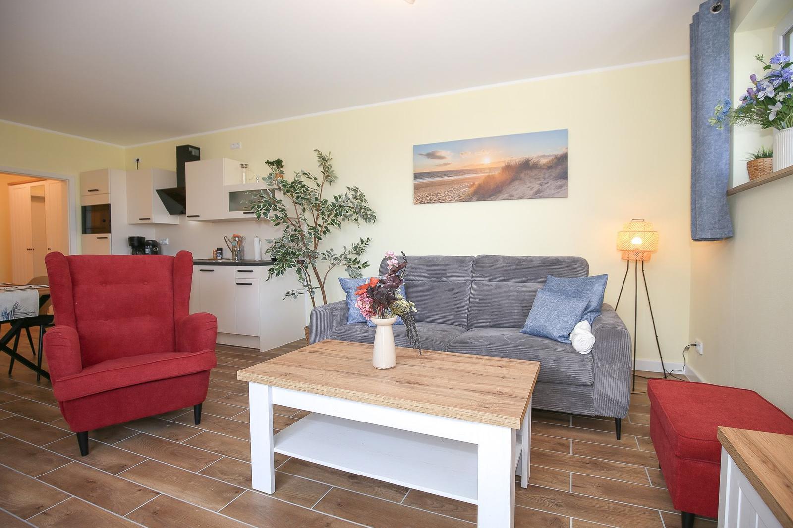 Wohnzimmer mit Sofa, roter Sessel und Küchenbereich