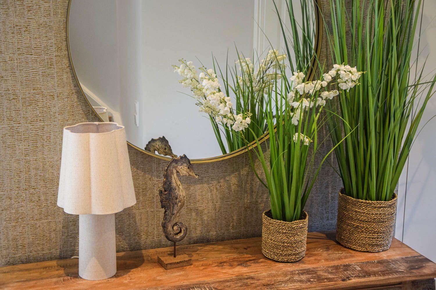 Holztisch mit Lampe, Pflanzen und Seepferdchenfigur vor Spiegel