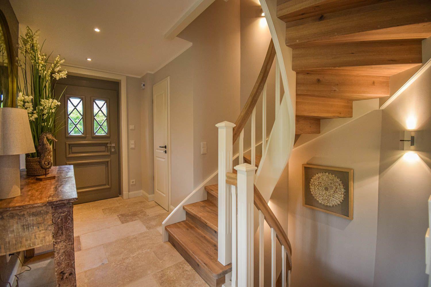 Eingang mit Holztreppe, Tisch mit Vasen und Wandbild.