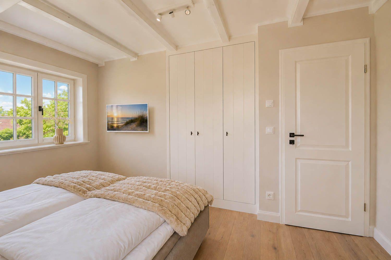 Schlafzimmer mit Bett, Kleiderschrank und Fenster mit Blick auf Grün.