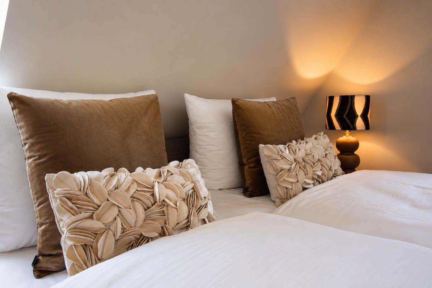 Ein Bett mit Kissen und einer Lampe an der Wand