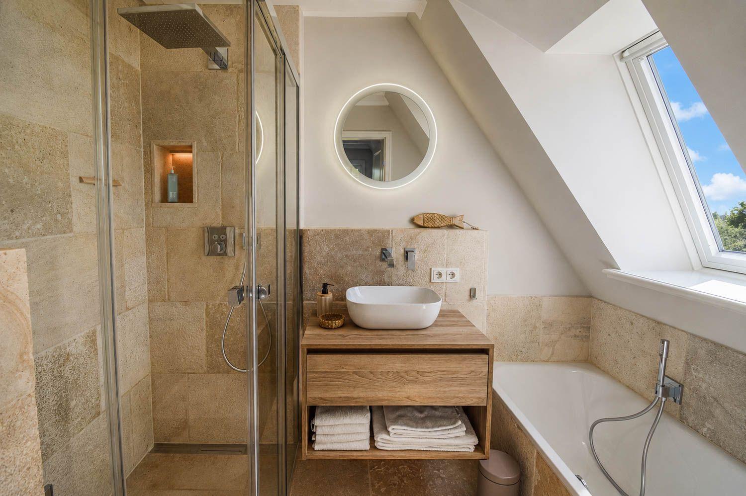 Dusche, Waschbecken und Badewanne in einem Dachbodenbad mit Fenster.
