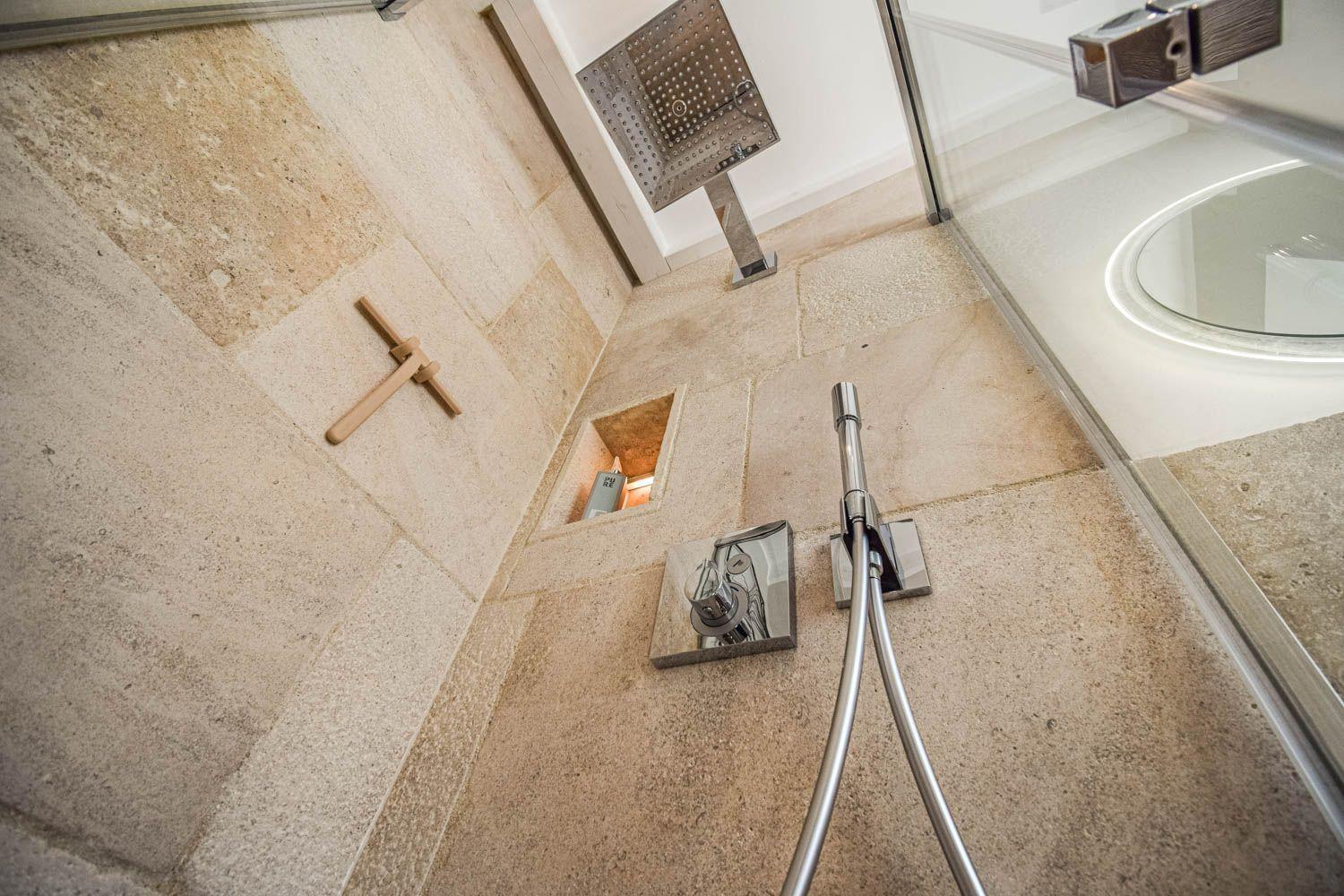 Dusche mit Steinwand, Duschbrause und Holzgriff