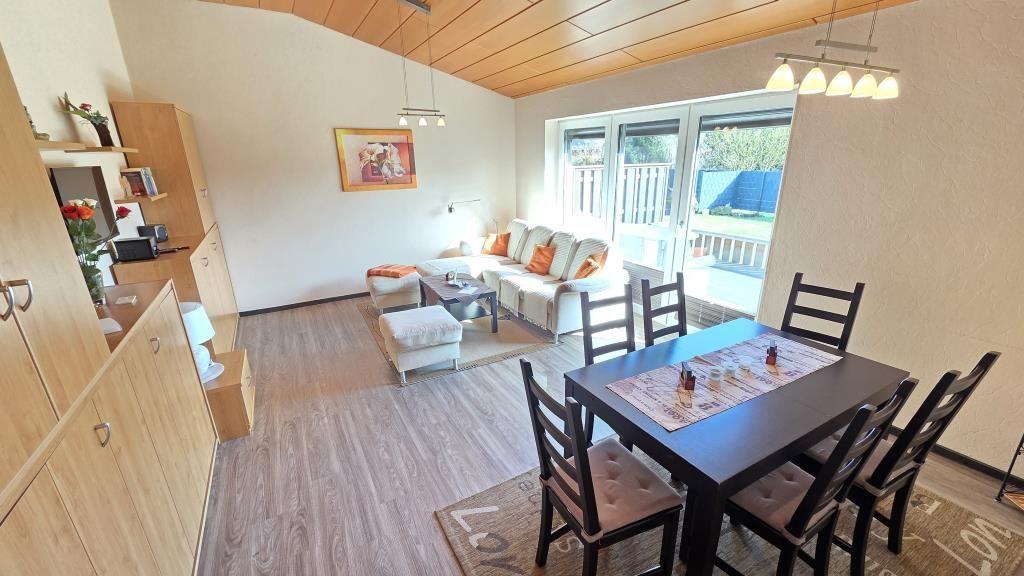 Wohn- und Essbereich mit Sofa, Esstisch und Terrassentür.