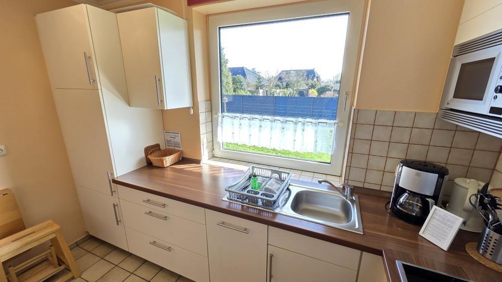 Küche mit Fenster, Spüle, Mikrowelle und Kaffeemaschine.