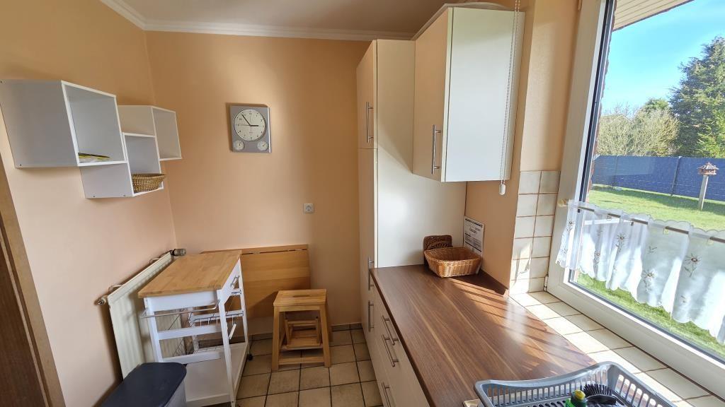 Küche mit Holz Arbeitsplatte, weißen Schränken und Blick auf Garten.
