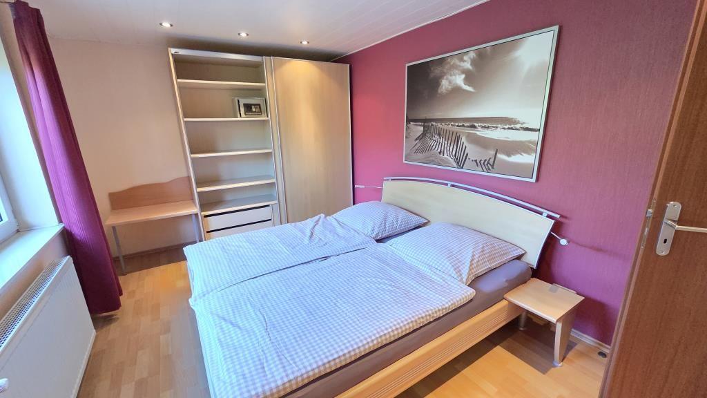 Schlafzimmer mit Doppelbett, Schwebetürenschrank und Wandbild.