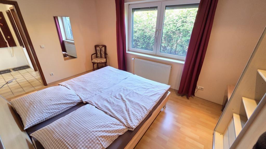 Schlafzimmer mit Doppelbett, Fenster und Holzboden.
