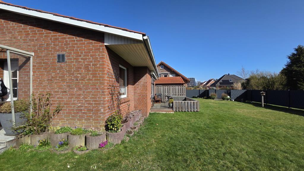 Hinterhof mit Grasfläche, Pflanzkübel und Terrasse an Backsteinhaus.