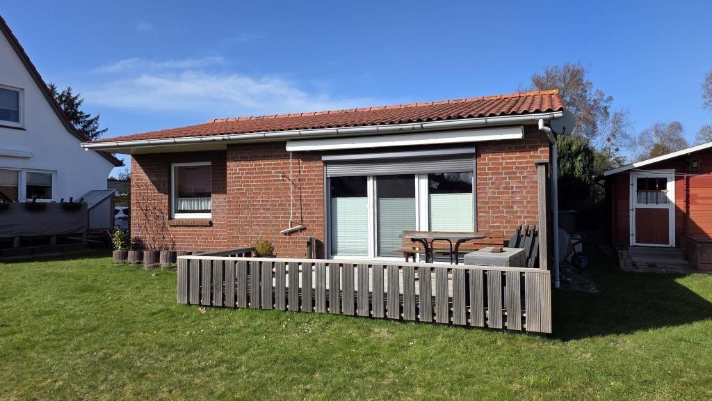 Einfamilienhaus mit Terrasse und Garten. Holzgeländer umgibt die Terrasse.