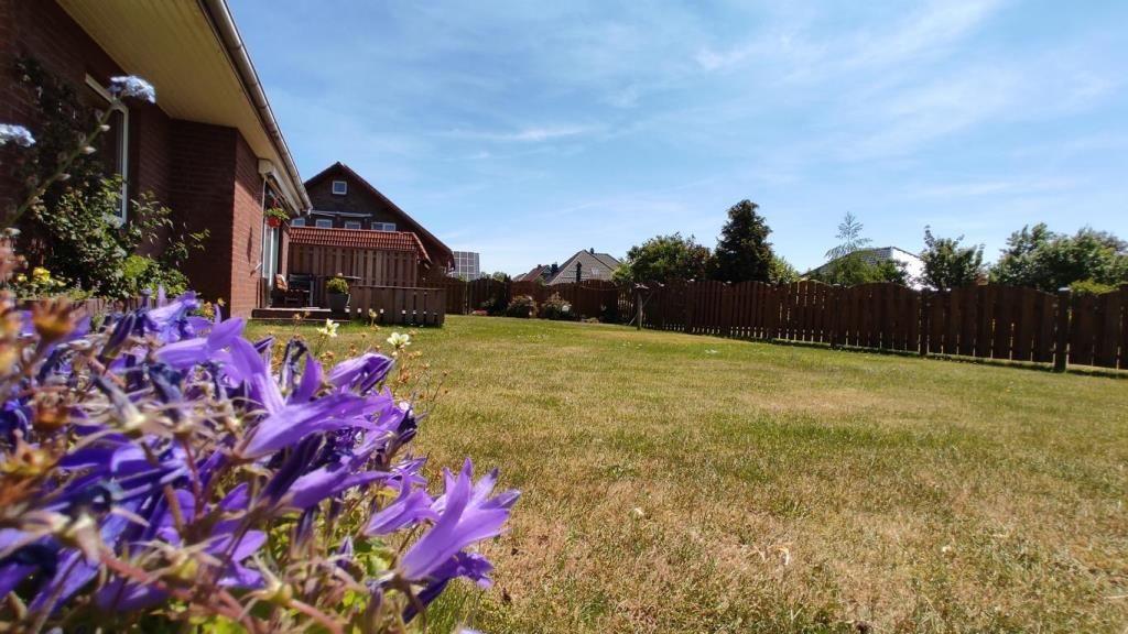 Garten mit Blumen vor einem Haus unter blauem Himmel.