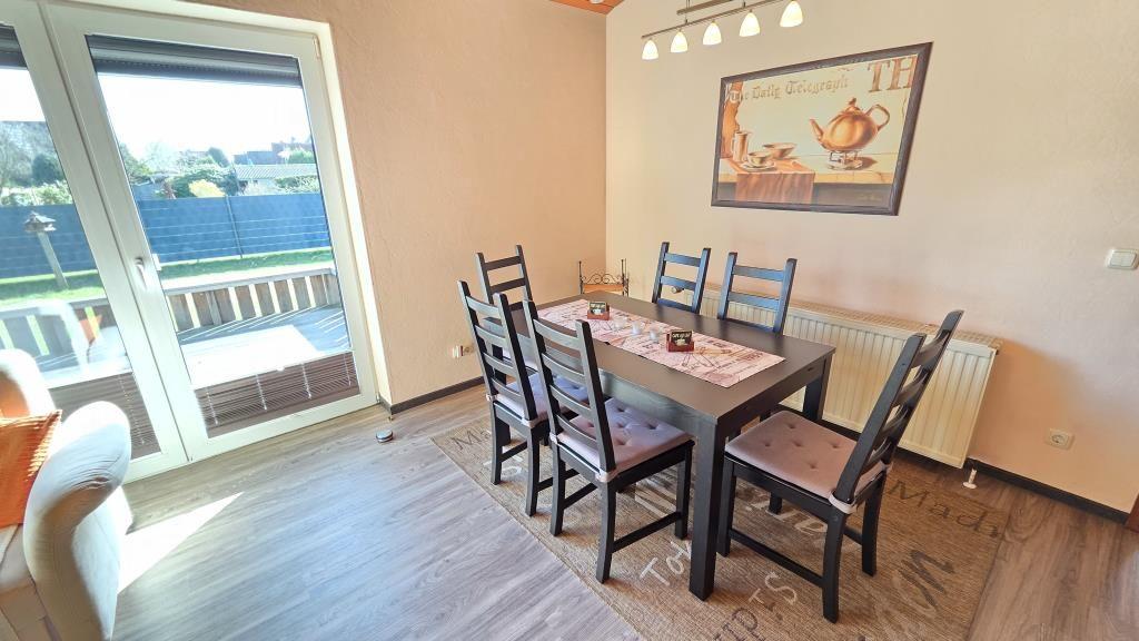 Esszimmer mit Tisch, sechs Stühlen und Glasfront zur Terrasse.
