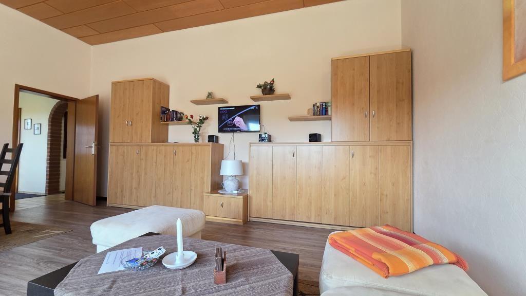 Wohnzimmer mit Holzmöbeln, Fernseher und Sitzgelegenheiten.