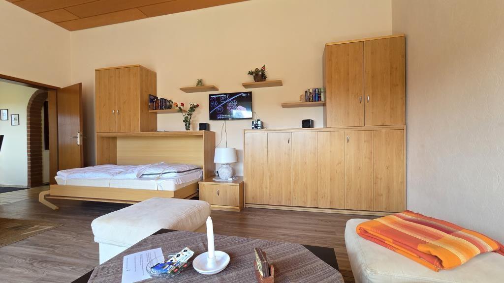 Schlafzimmer mit Bett, Schränken und Fernseher an der Wand.