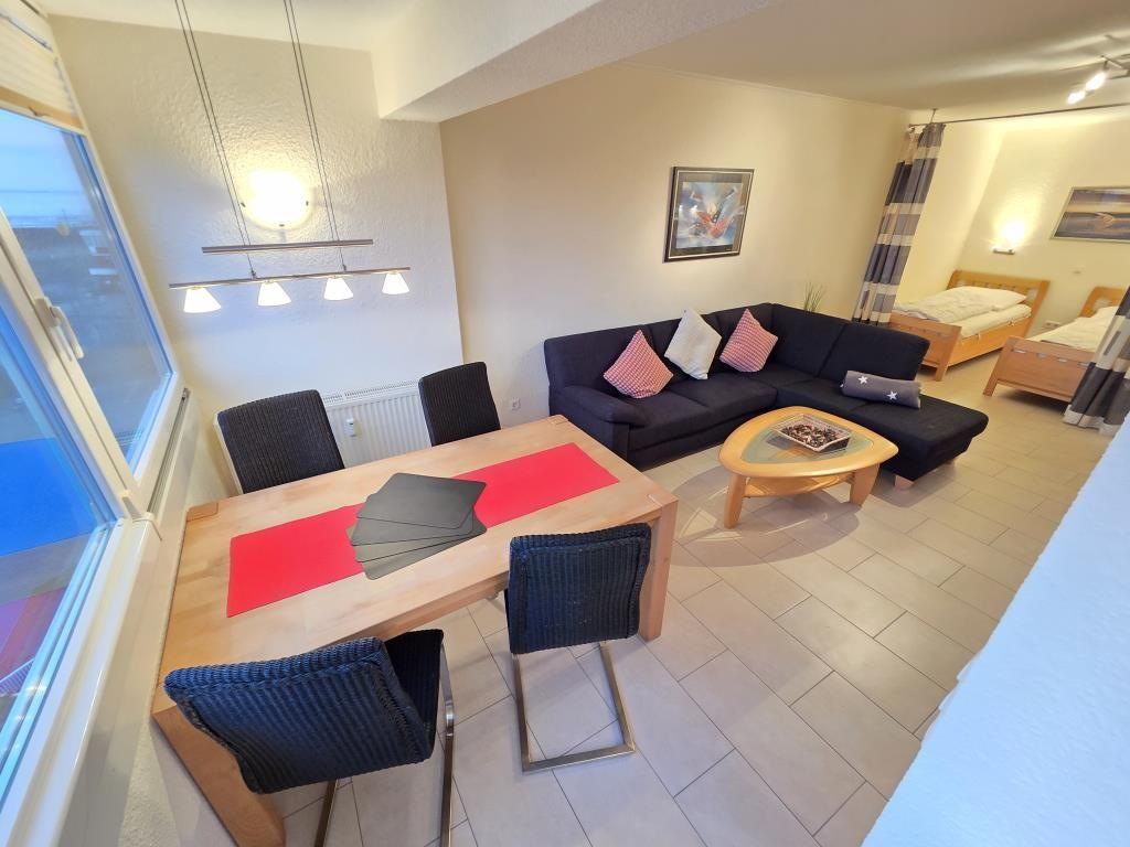 Wohnzimmer mit Sofa, Esstisch und zwei Schlafzimmern mit Betten.