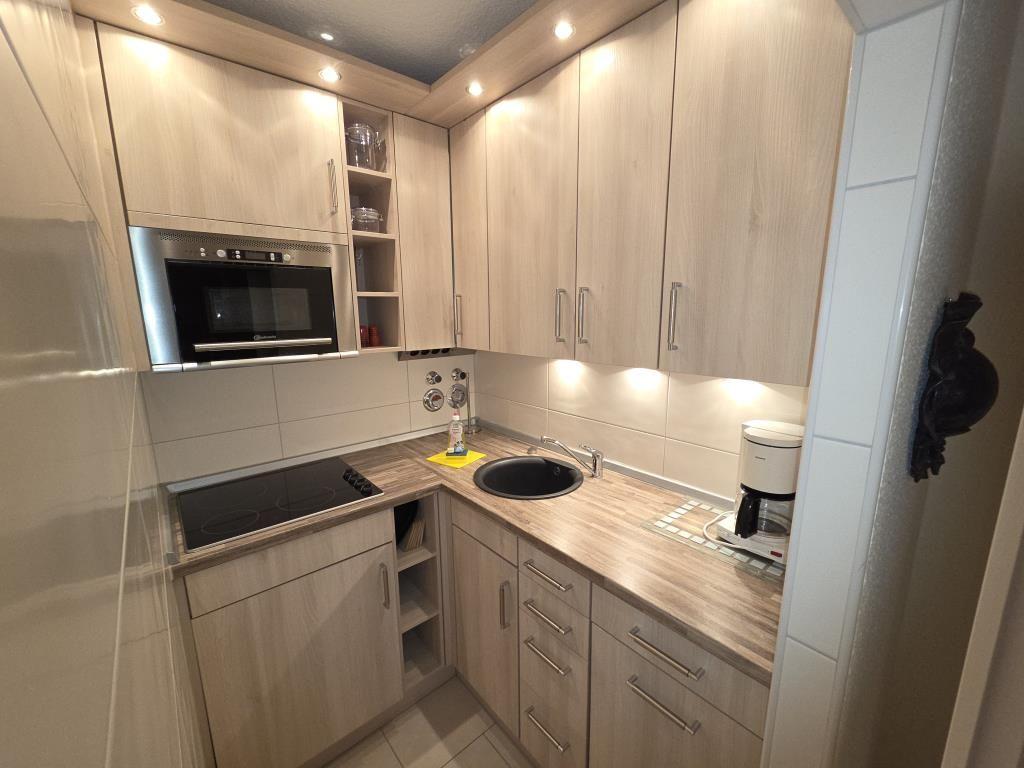 Moderne Küche mit Holzschränken, Spüle und Einbauherd.
