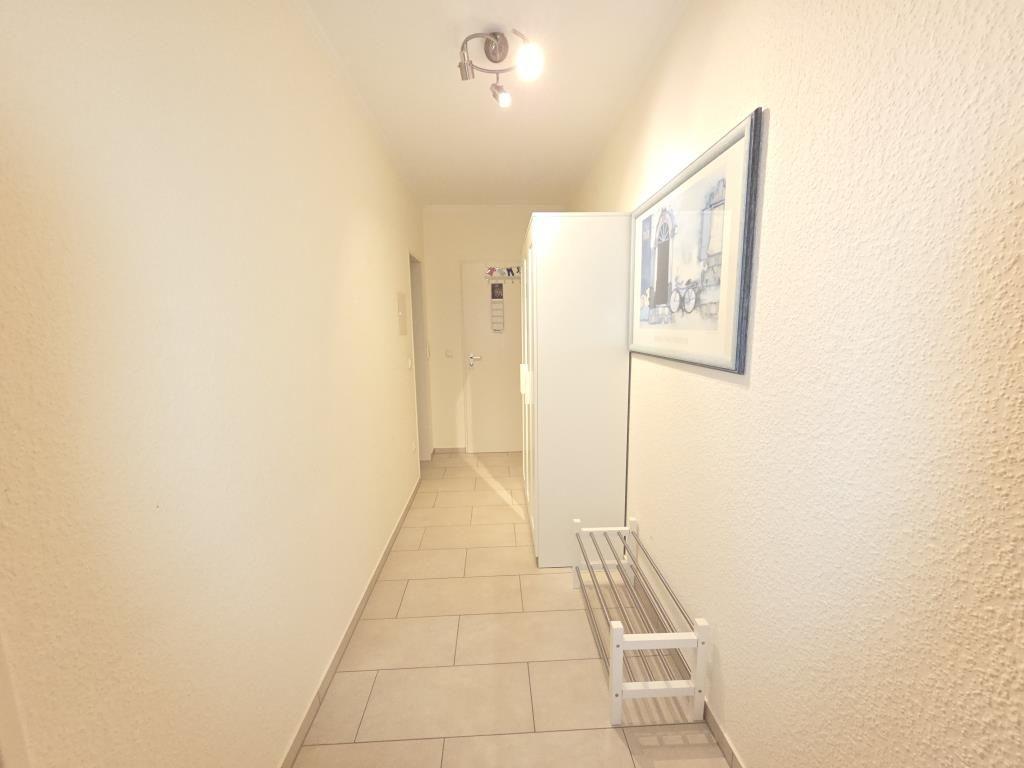 Flur mit Wandbild, Kleiderständer und weißen Wänden.