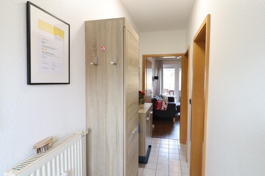 Flur mit Kleiderschrank, Heizkörper und Blick in Wohnzimmer.