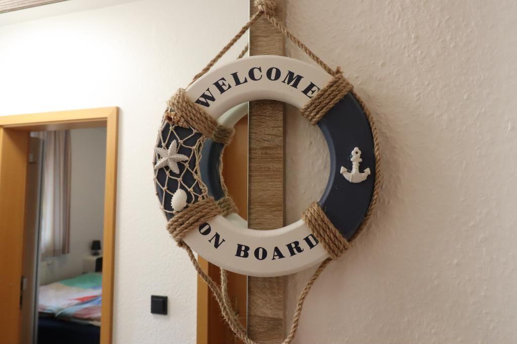 Willkommens-Schild mit Segelbootmotiv an der Wand